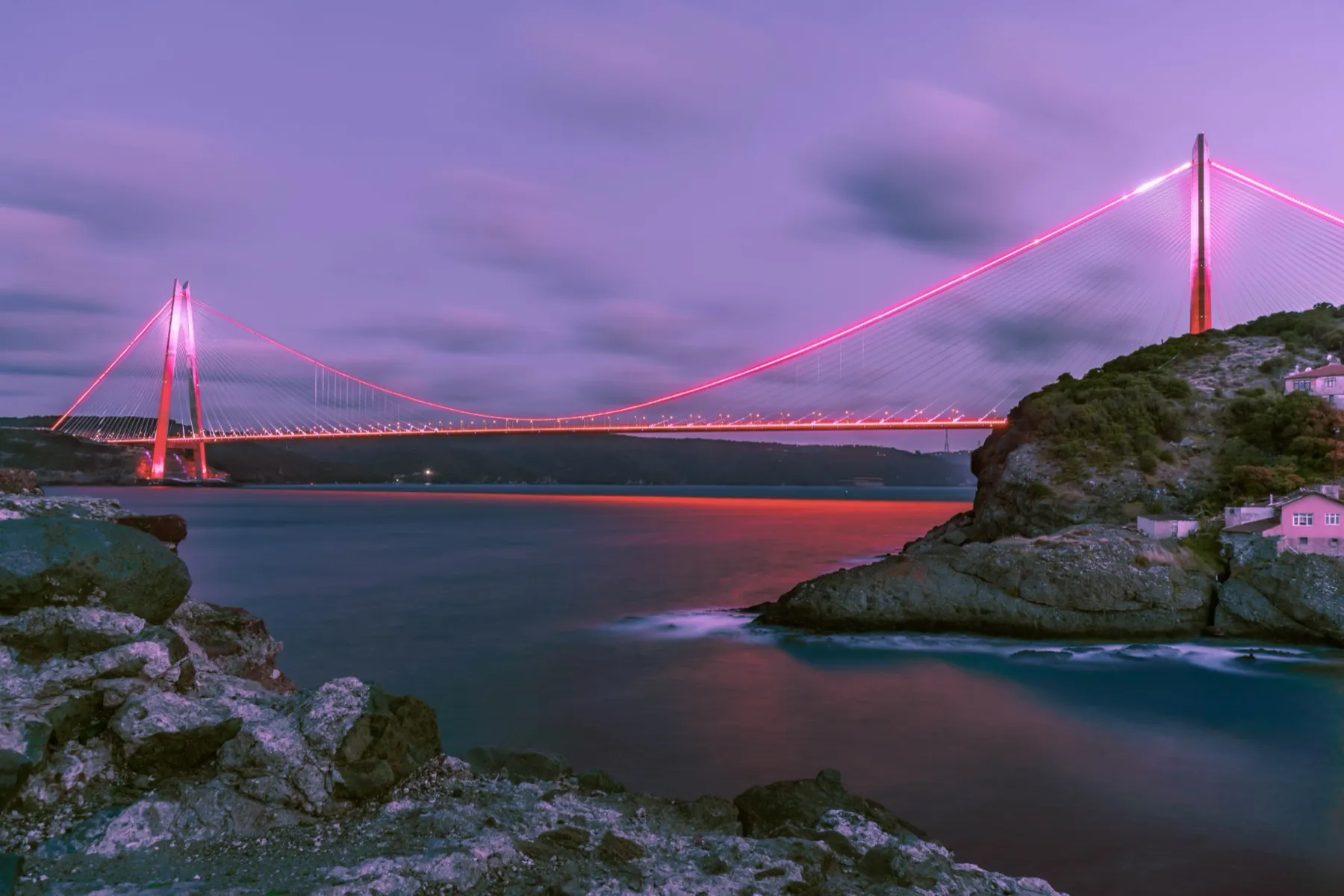 A Bosphorus bridge lit at dusk above a rocky shore